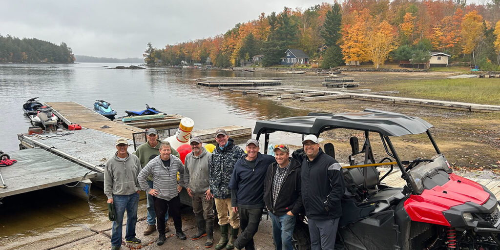 group of men standing beside trailer of buoys in front of lake